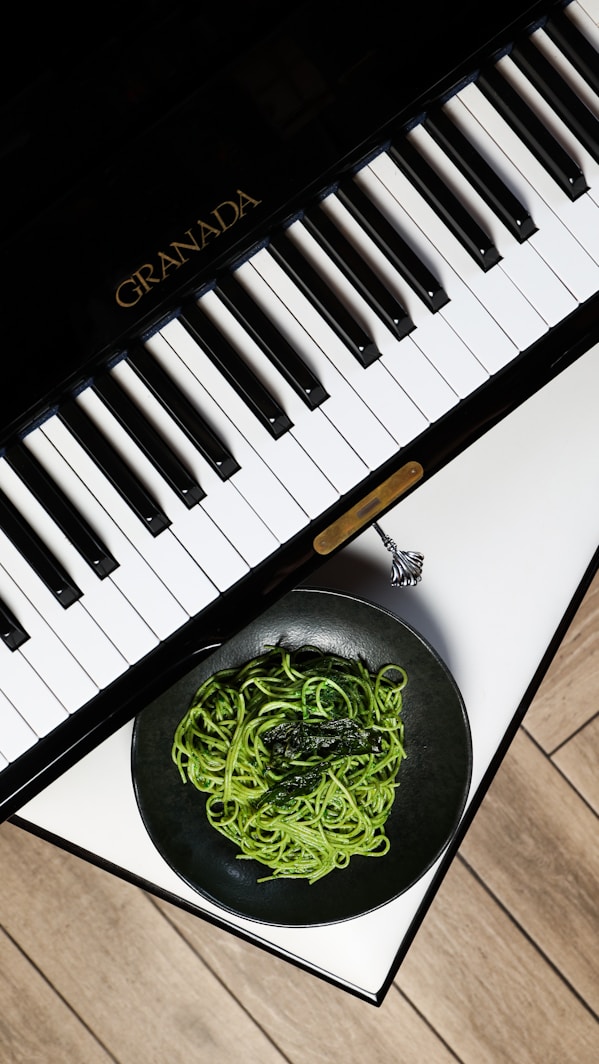 A bowl of noodles is next to a piano keyboard