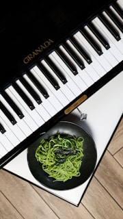 A bowl of noodles is next to a piano keyboard