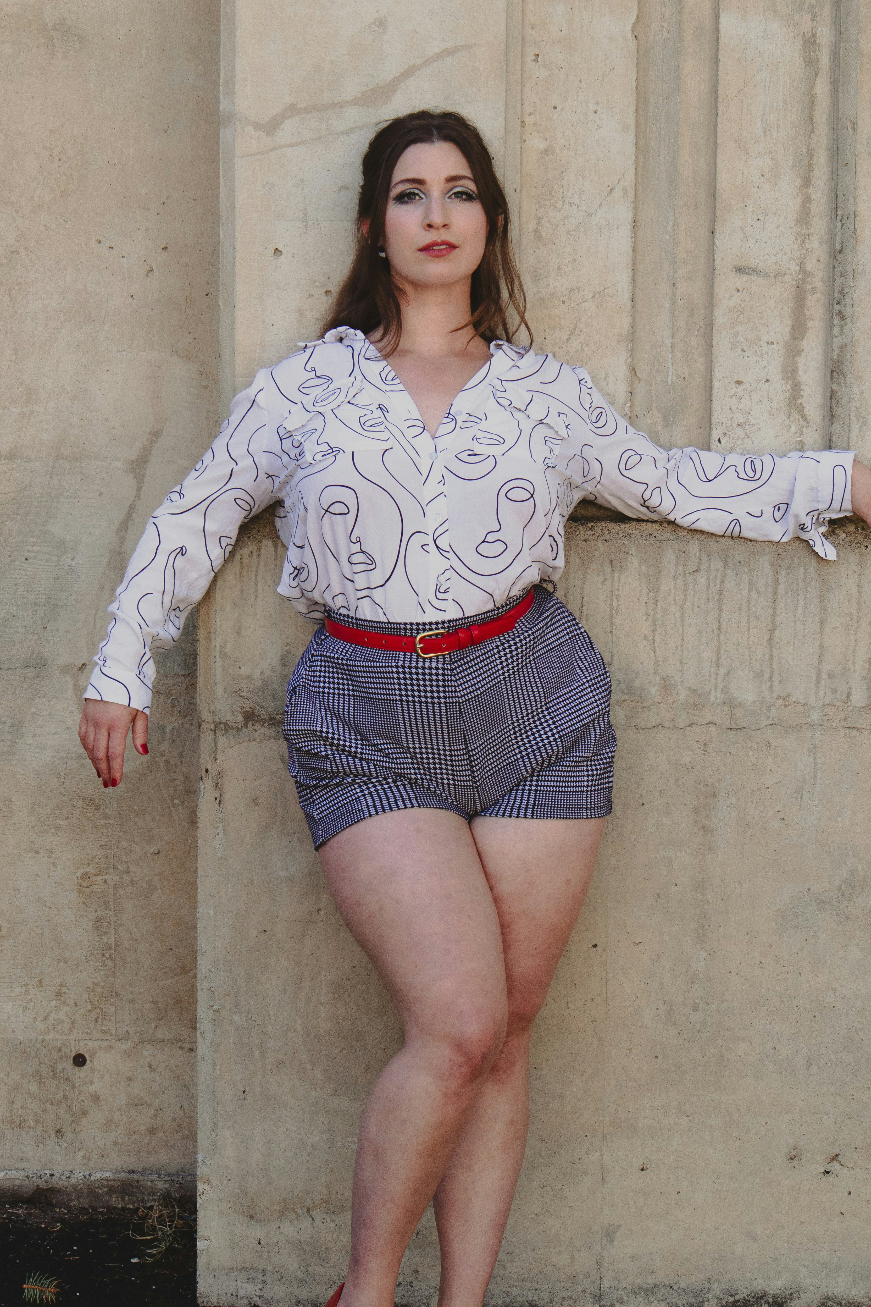 A woman leaning against a wall with her hands on her hips photo – Free ...