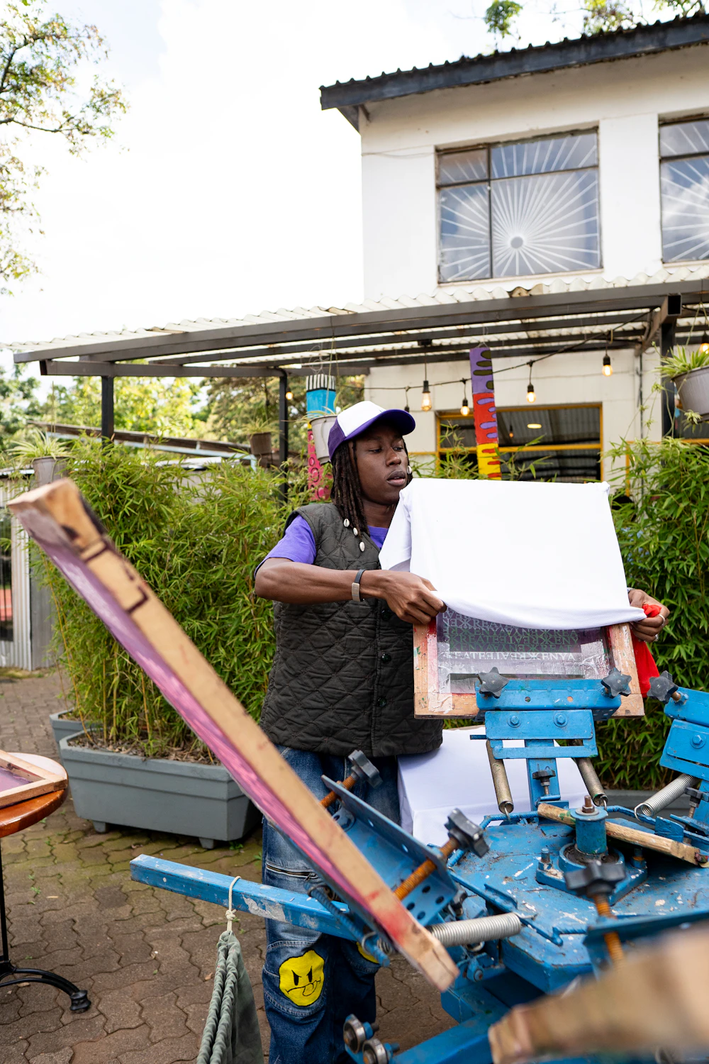A small-business owner screen-printing fabric at an outdoor workshop in Nairobi