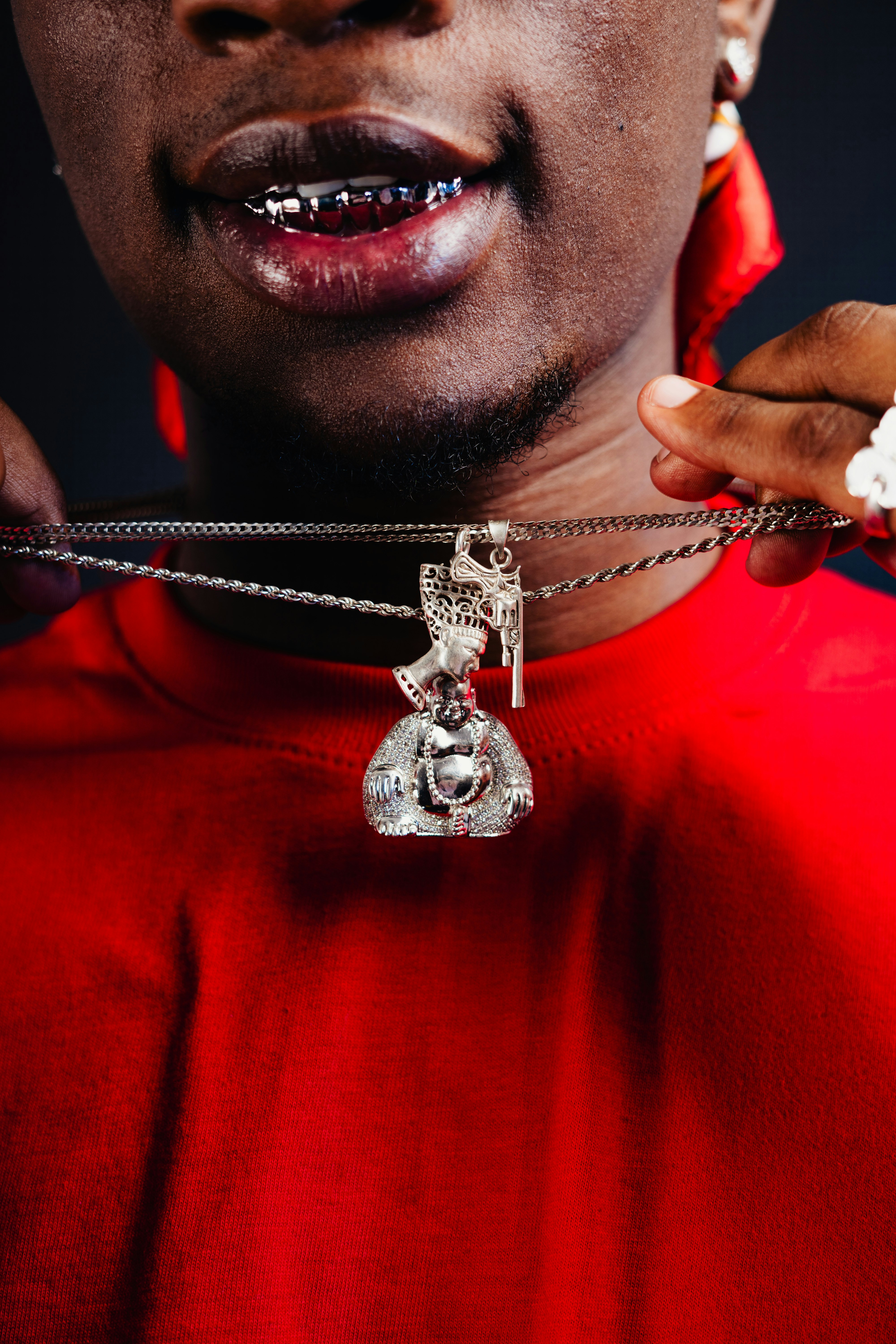 A man wearing a red shirt holding a silver necklace