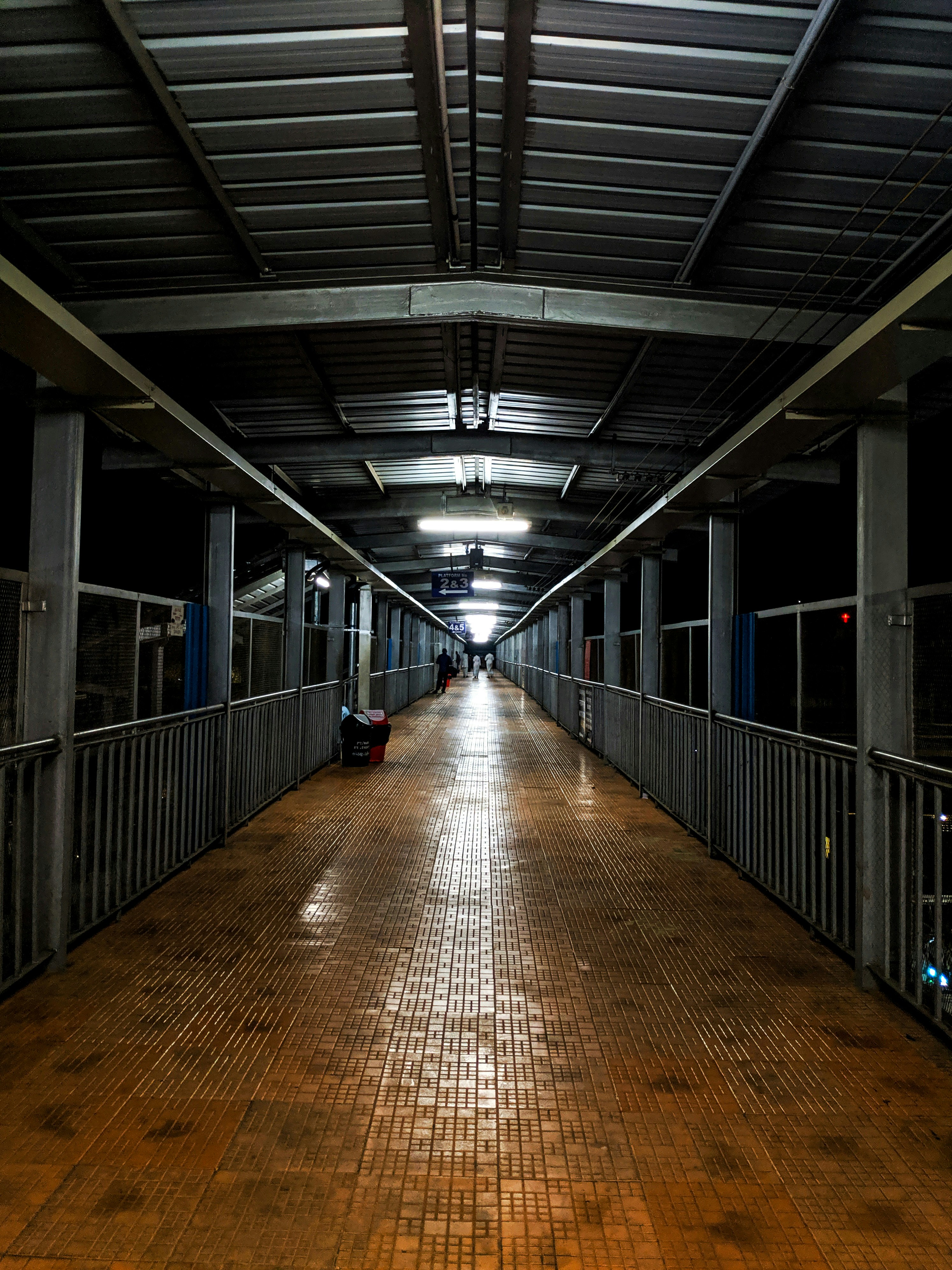 A long hallway with a wooden floor and metal railings