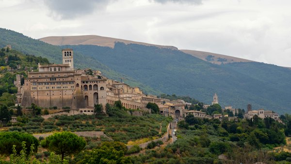 A village on a hill with mountains in the background — Assisi, Italy