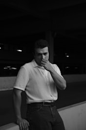 A man in a white shirt is leaning against a wall