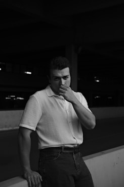 A man in a white shirt is leaning against a wall