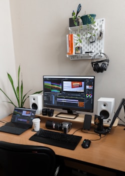 A desk with a computer, speakers and a laptop on it
