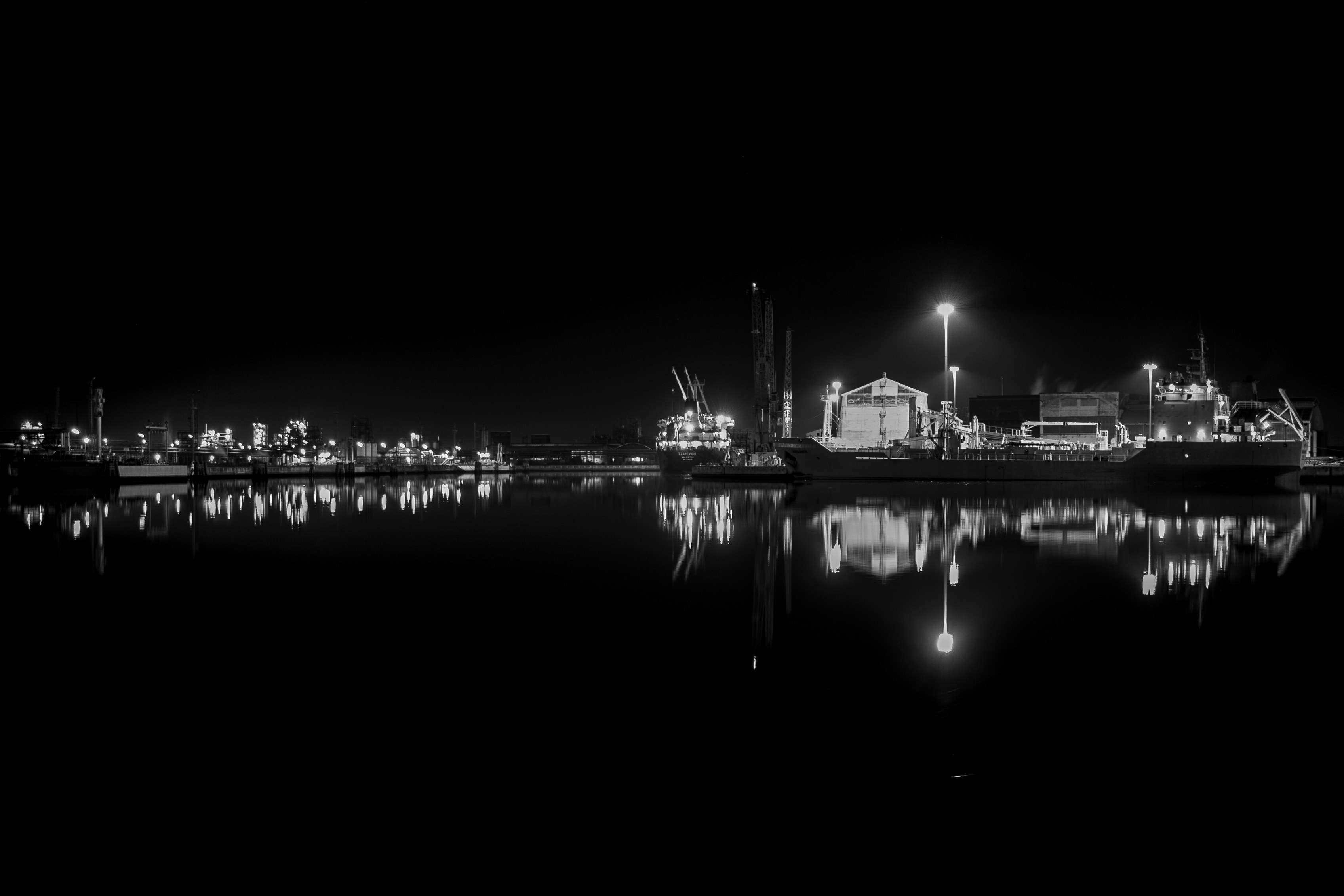 Industrial port at night with shipping containers, dark atmospheric, minimal lighting, deep shadows