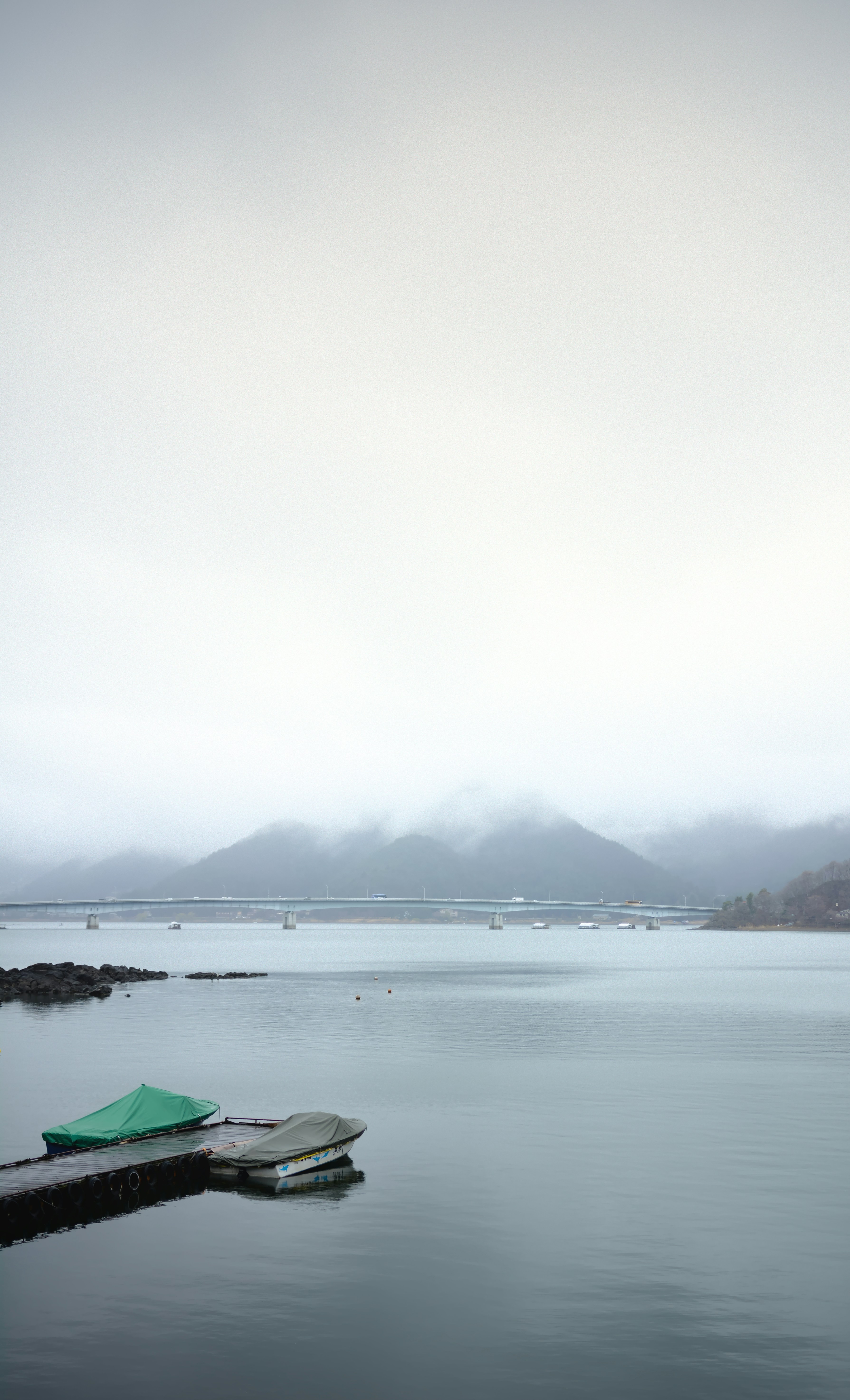 A green umbrella sitting on the end of a dock