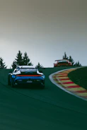 Two cars driving on a race track with trees in the background