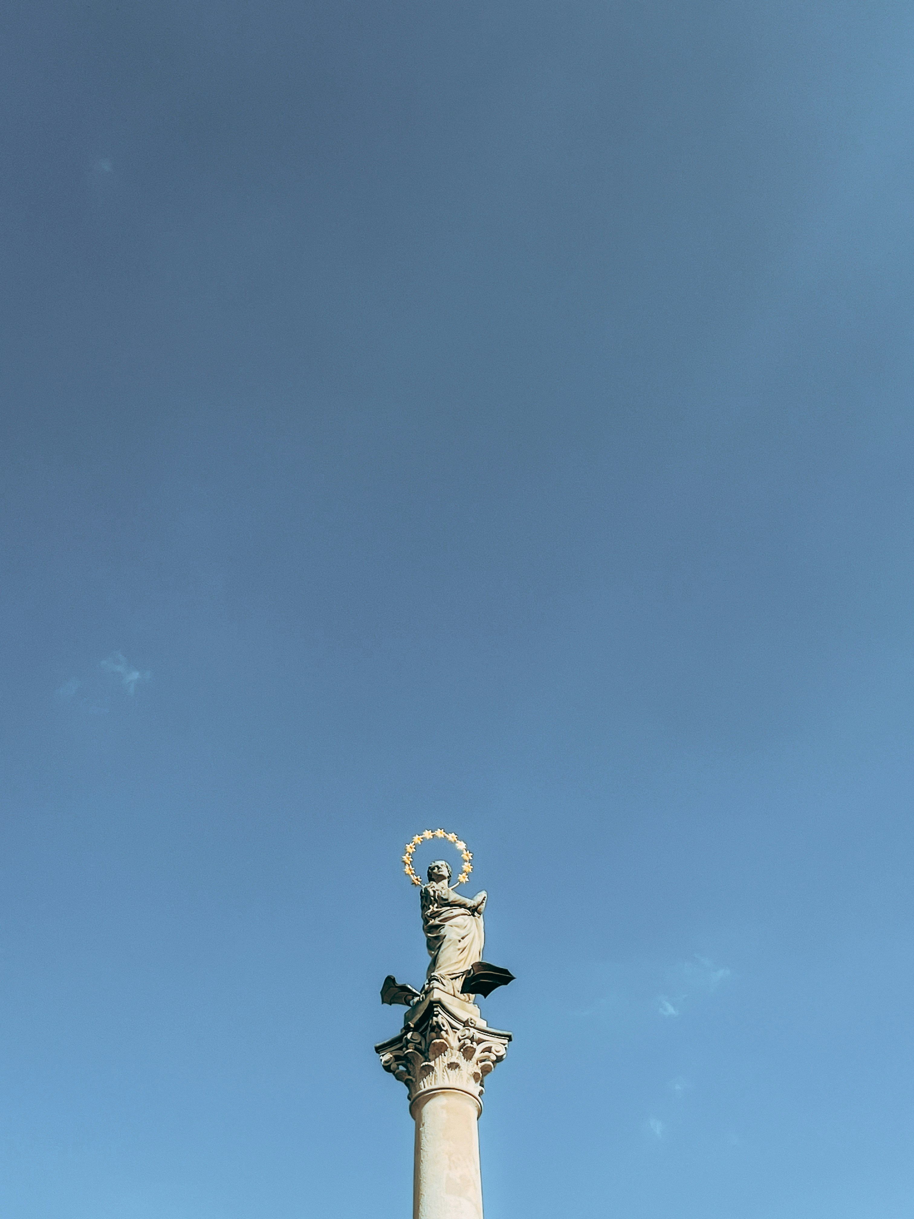 A tall white pillar with a statue on top of it