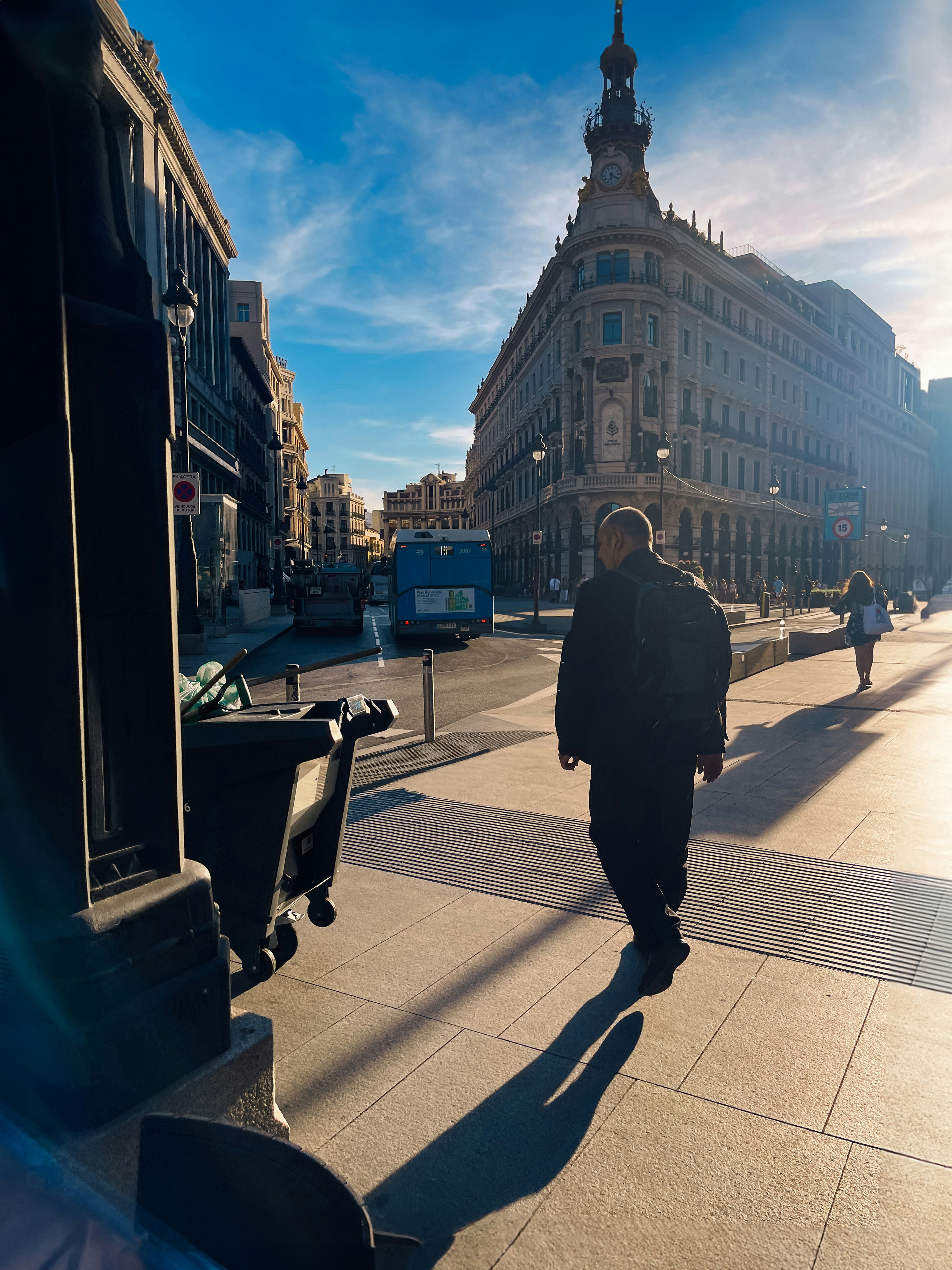 고층 건물 옆 거리를 걷고 있는 남자