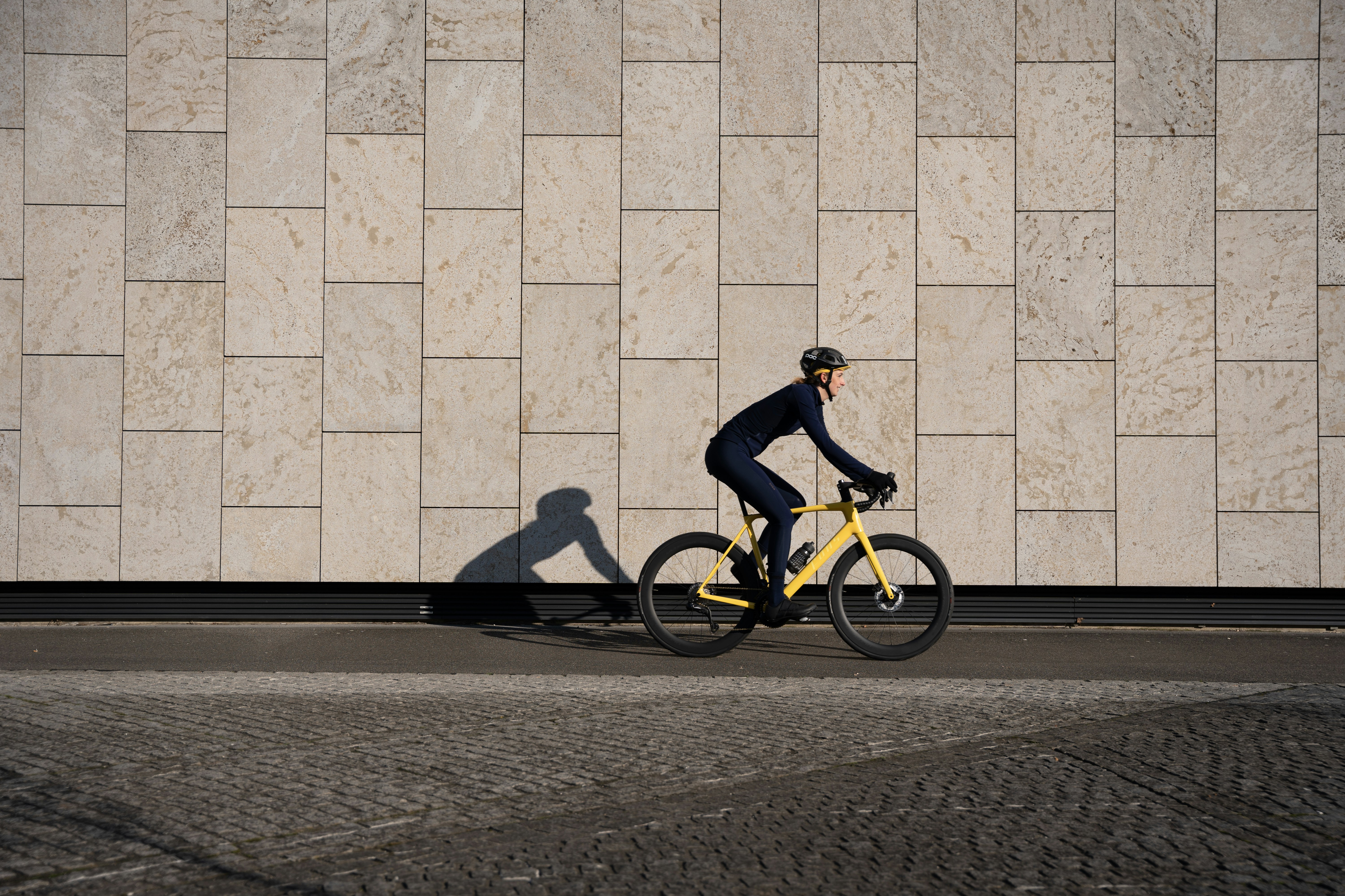A man riding a bike next to a wall