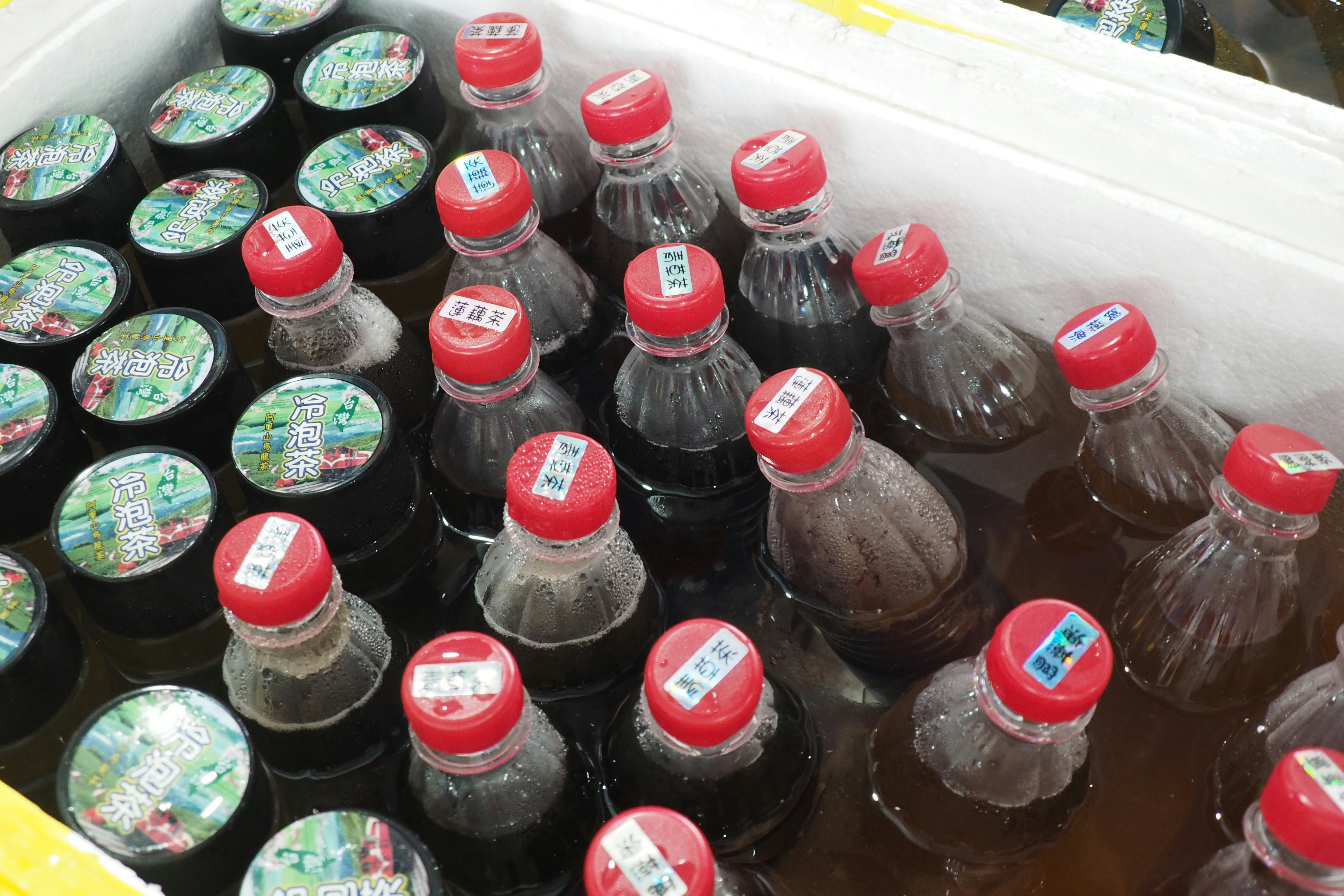 Bottles of soda are lined up in a cooler