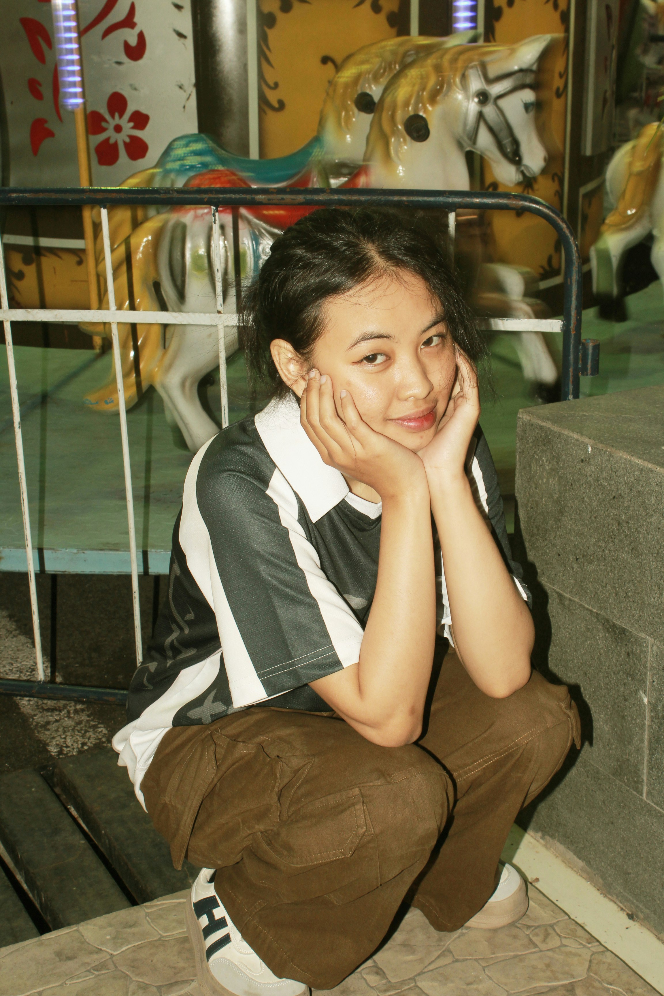 A woman sitting on the ground in front of a carousel