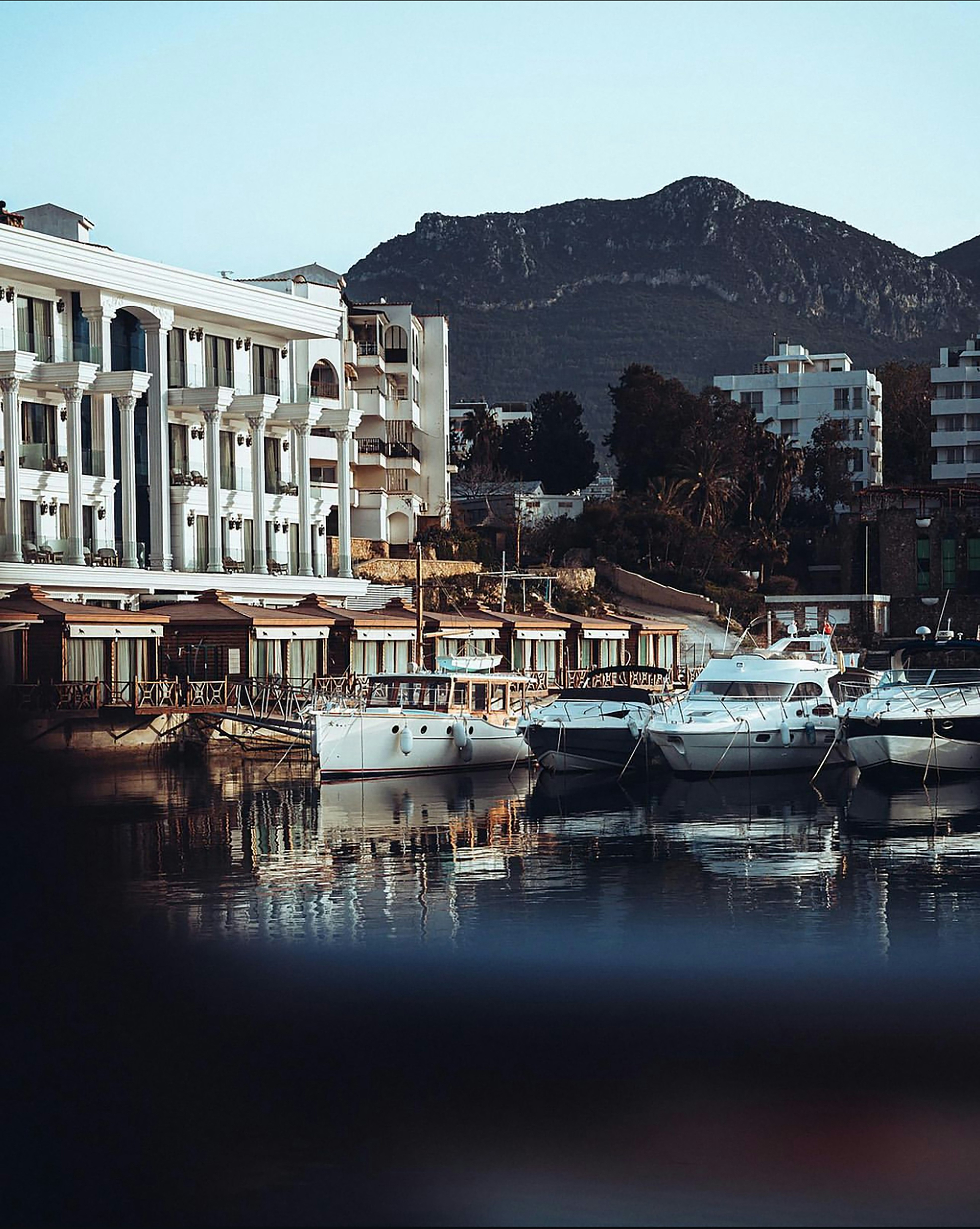 Luxury expedition vessel navigating through arctic ice floes with dramatic mountain backdrop