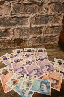 A pile of foreign currency sitting on top of a wooden table