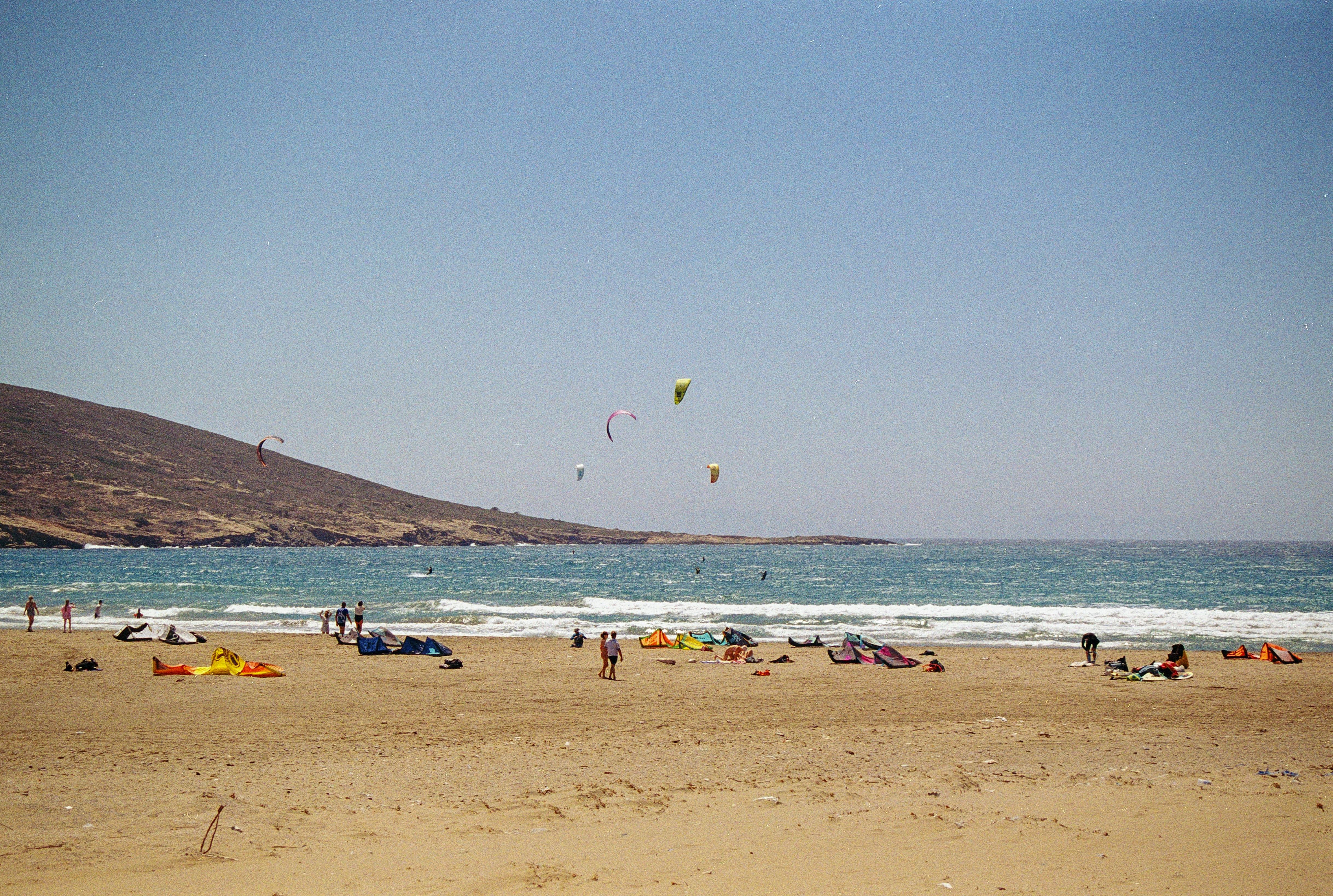A group of people standing on top of a sandy beach, 
