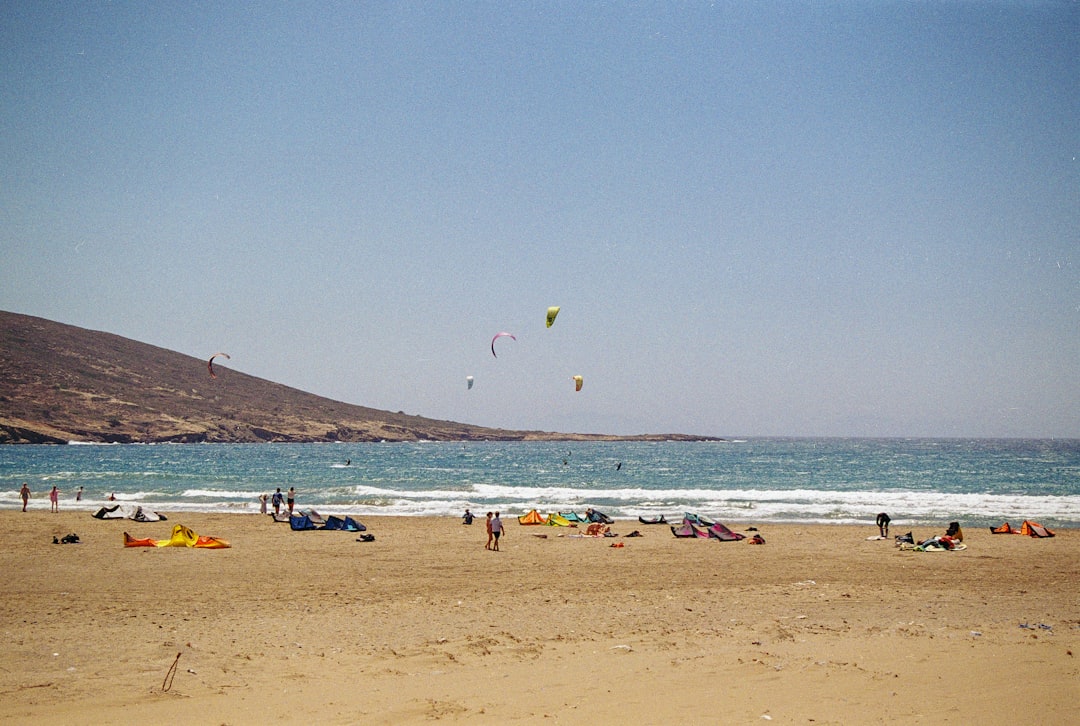 A group of people standing on top of a sandy beach,