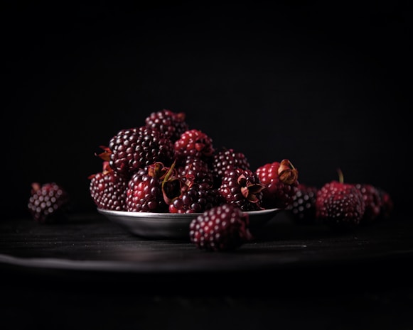 A metal bowl filled with lots of blackberries