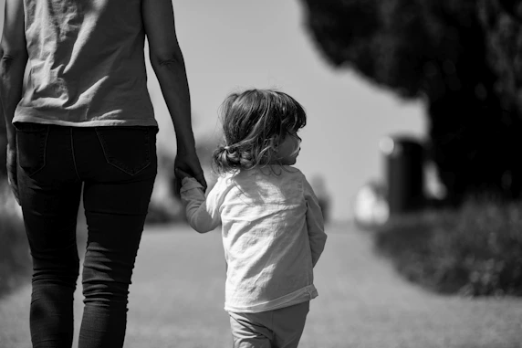 A woman holding the hand of a small child