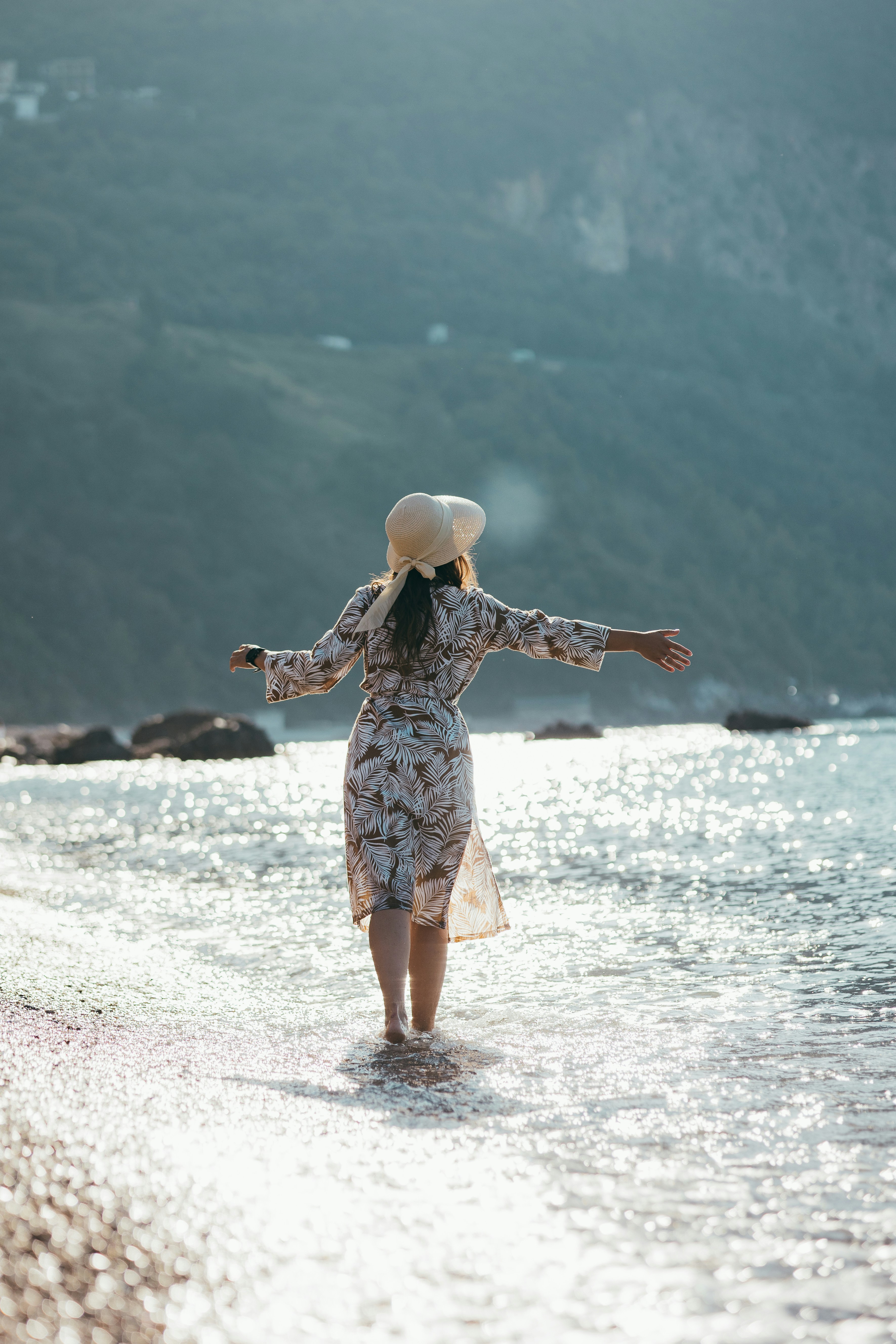 A woman walking along a beach next to the ocean