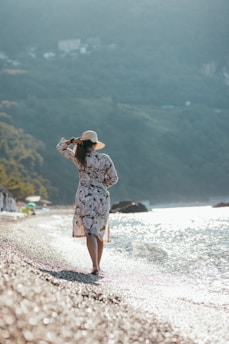 A woman walking along a beach next to the ocean