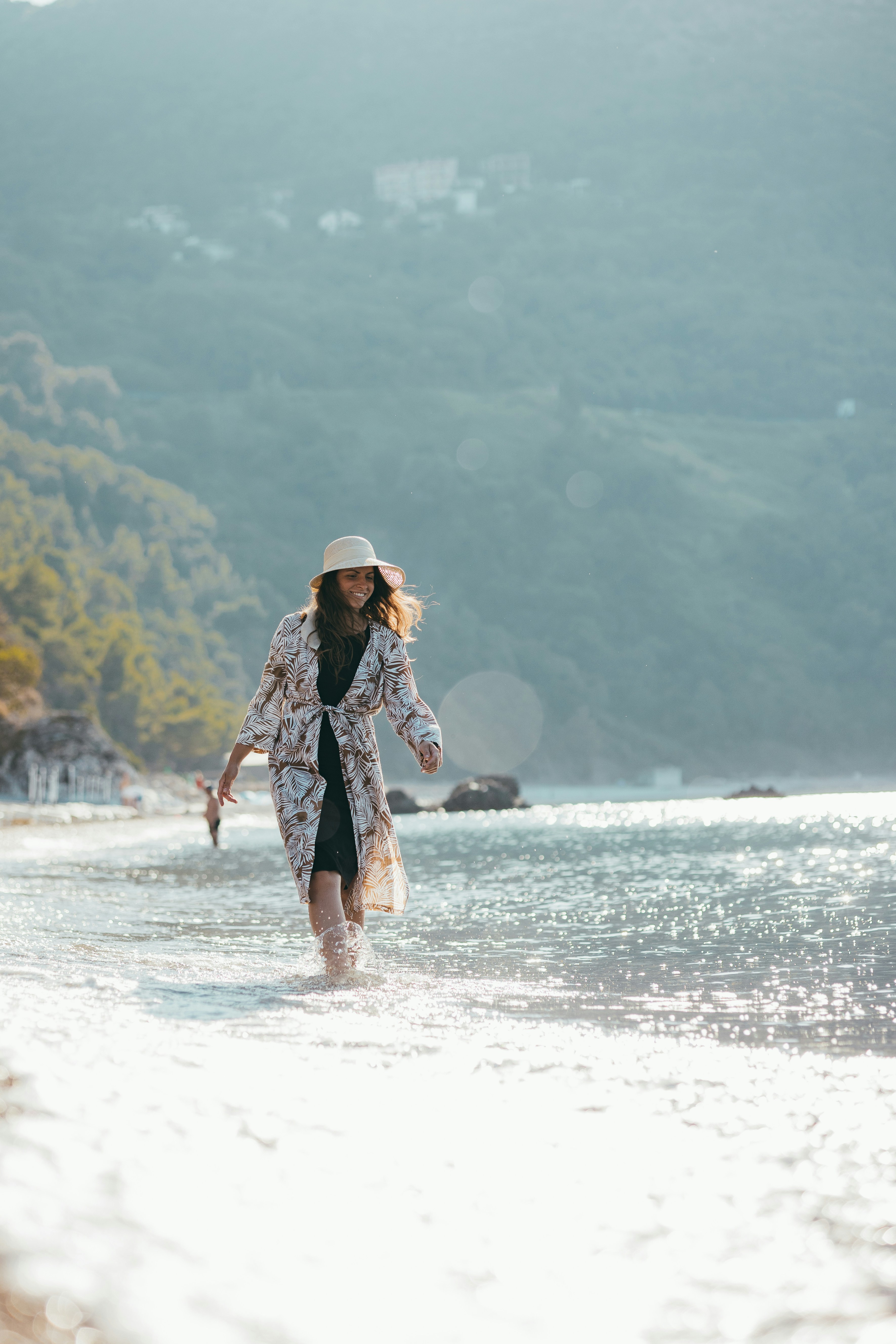 A woman walking along a beach next to the ocean