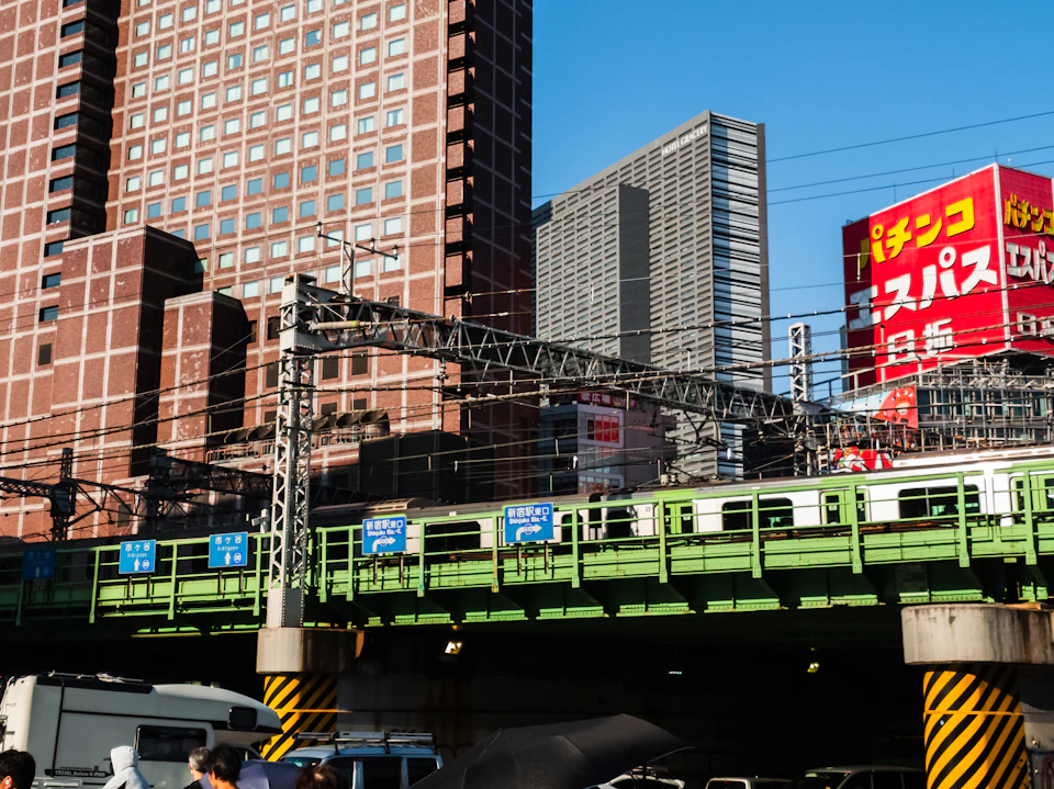 Train crosses elevated green bridge with Japanese characters and contrasting green and white train