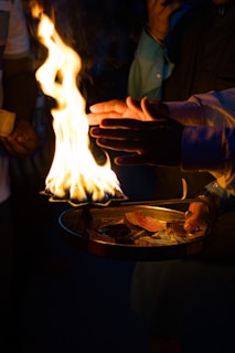 A person holding a plate of food with flames coming out of it