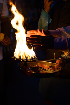 A person holding a plate of food with flames coming out of it