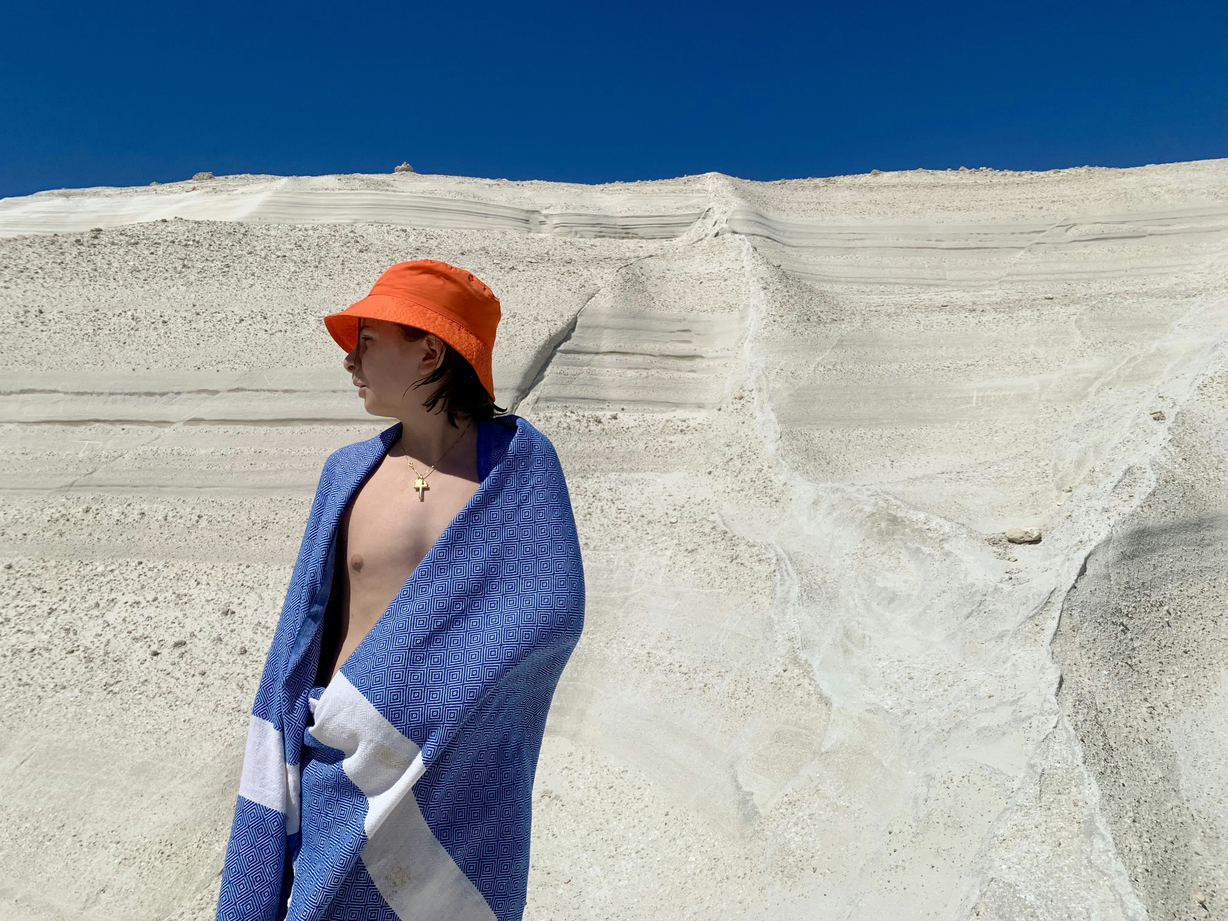 A woman wrapped in a towel standing on a beach, 