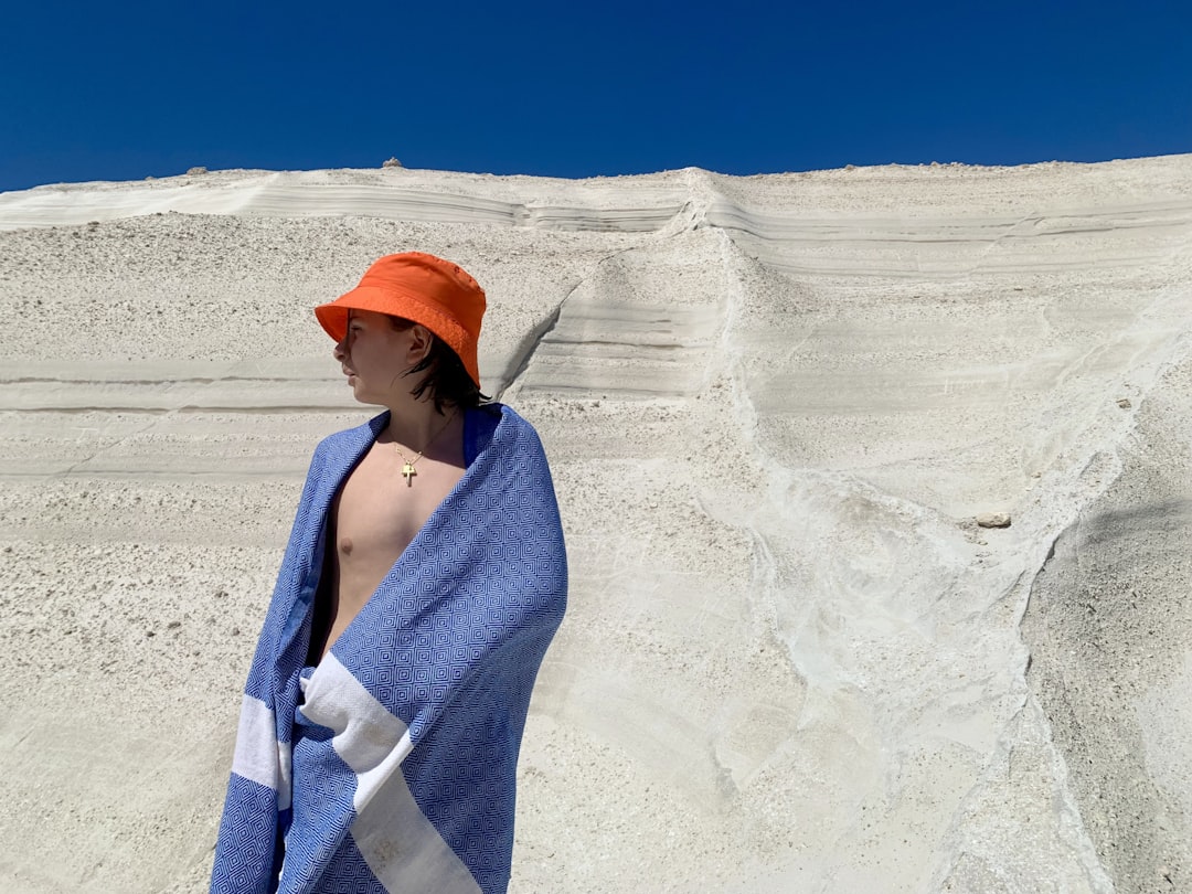 A woman wrapped in a towel standing on a beach,