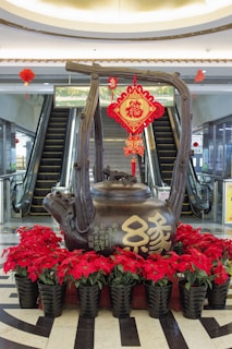A statue of a teapot with flowers in front of it