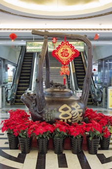 A statue of a teapot with flowers in front of it