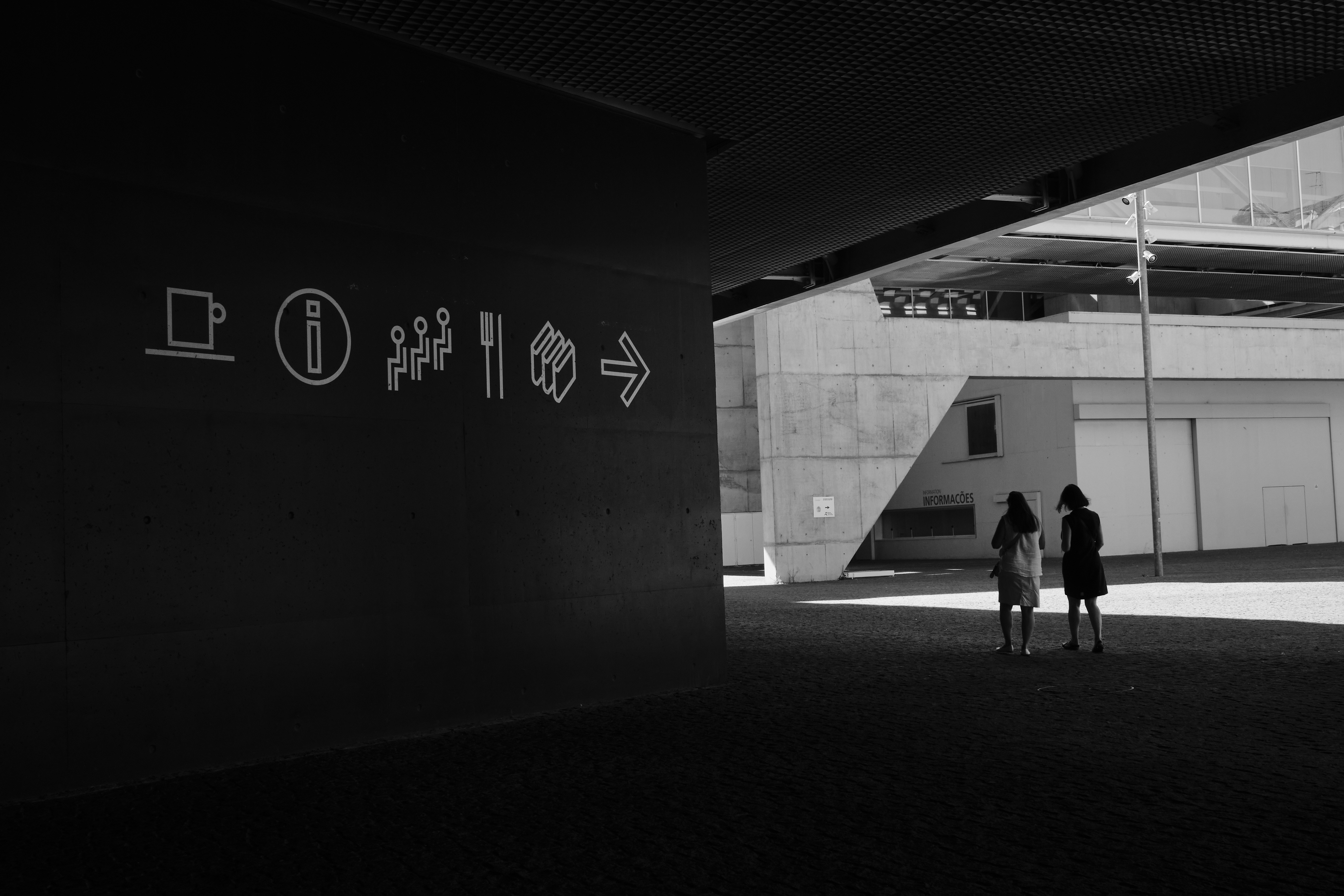 A black and white photo of two people walking in a tunnel
