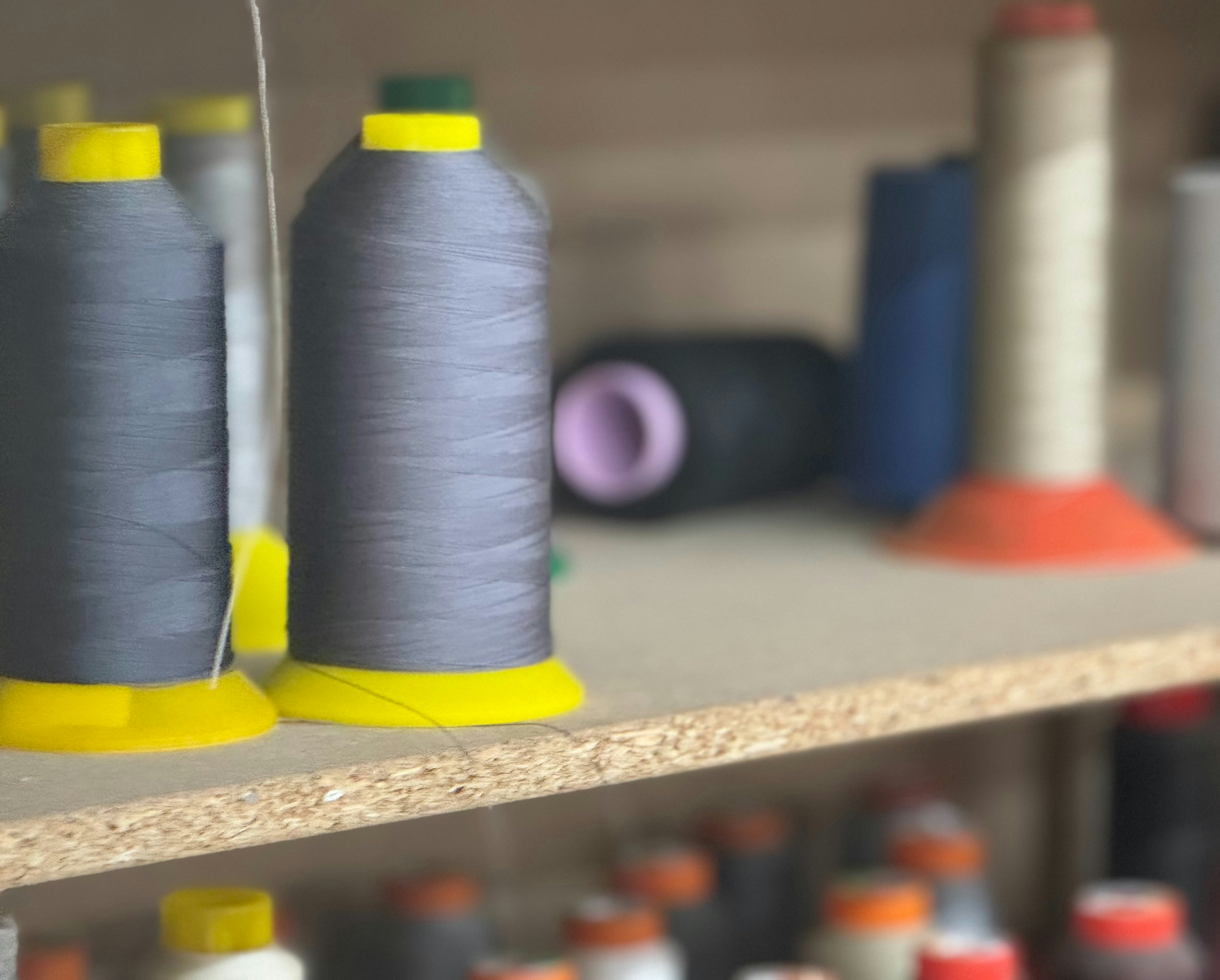 Two spools of thread sit on a shelf