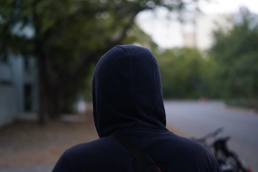 A person in a black hoodie standing on a street