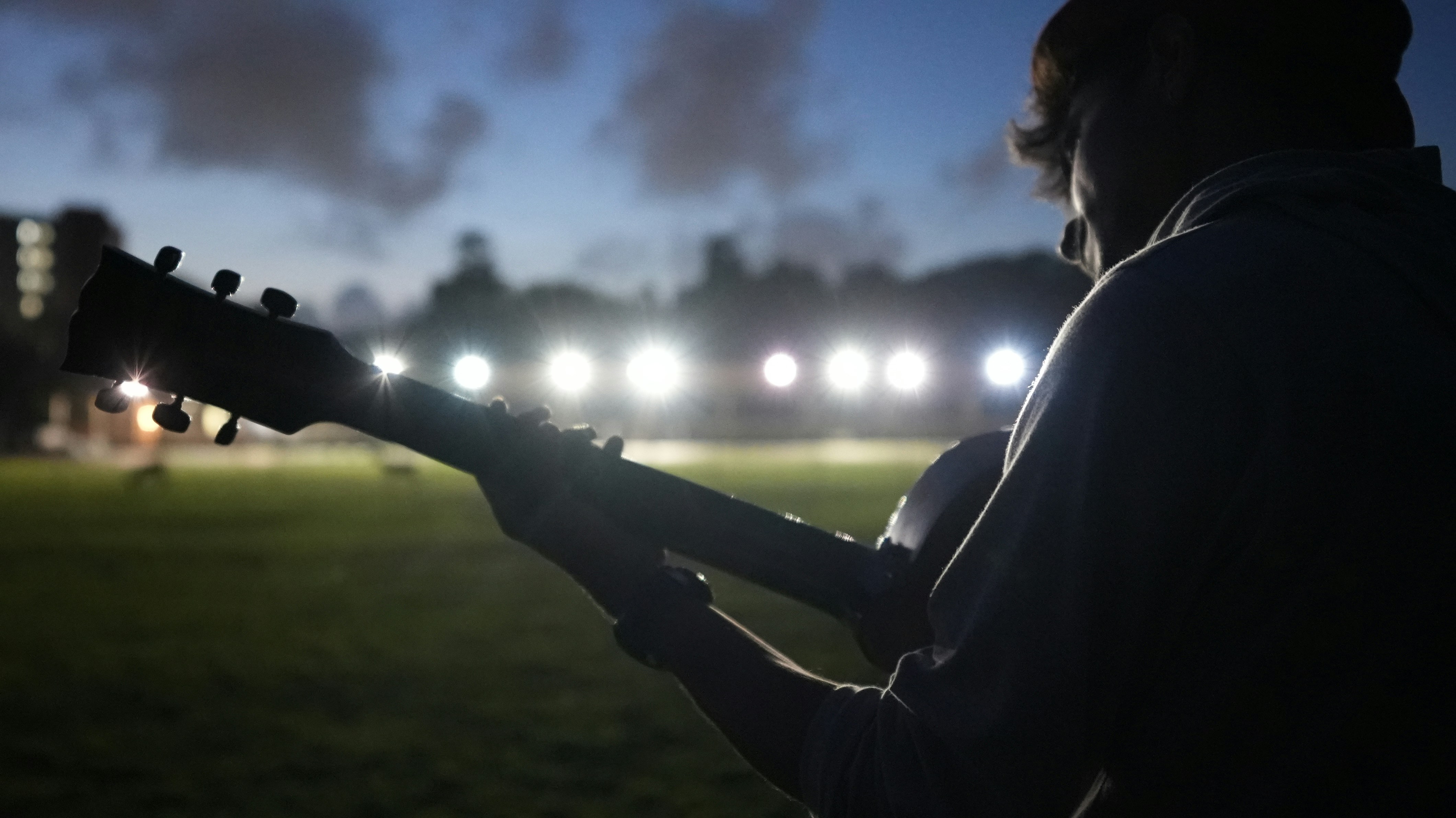 Un uomo che suona una chitarra in un campo di notte