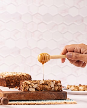 A person drizzling honey onto a piece of bread