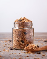 A jar filled with granola next to a wooden spoon