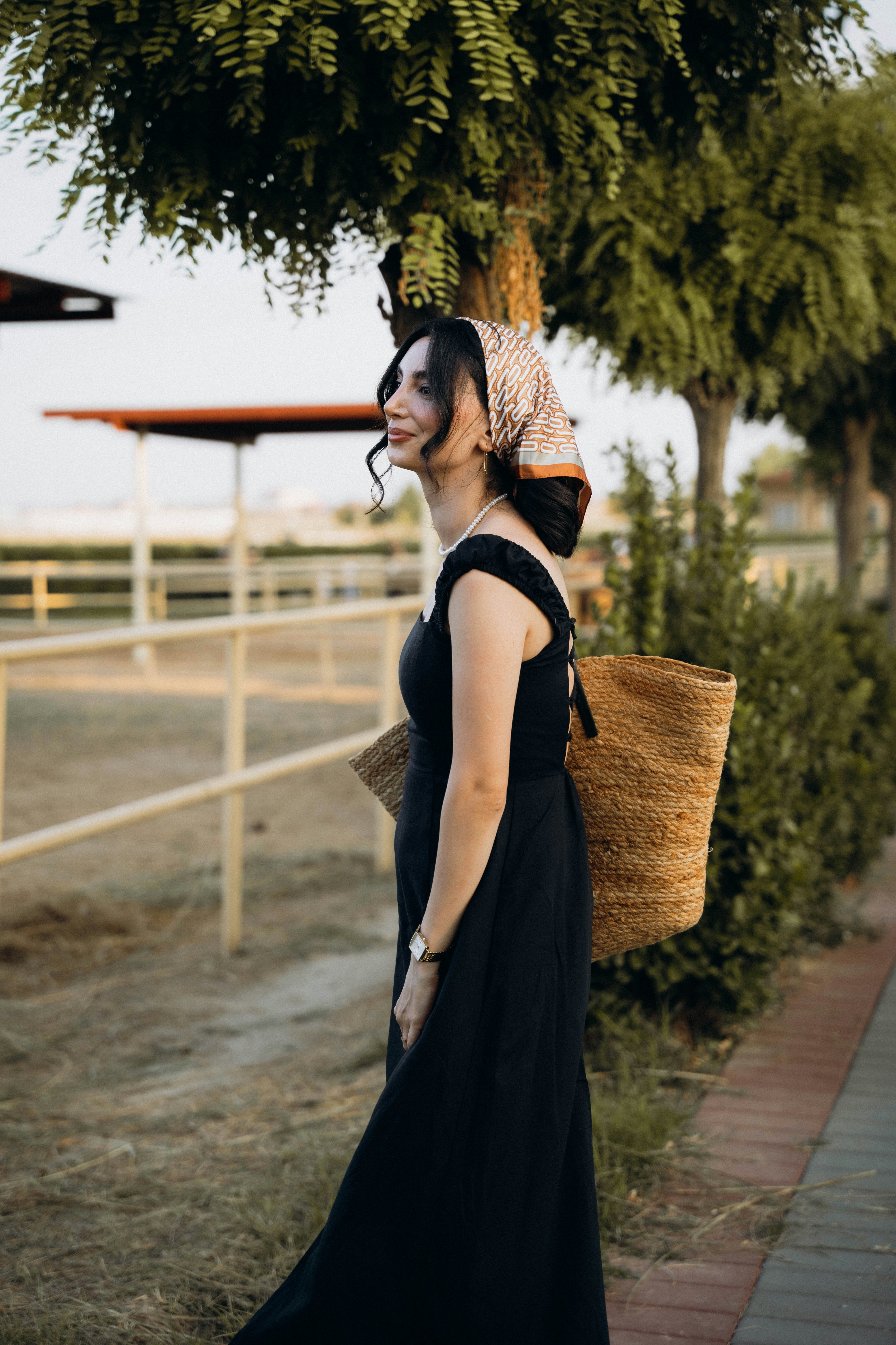 A woman walking down a sidewalk carrying a basket