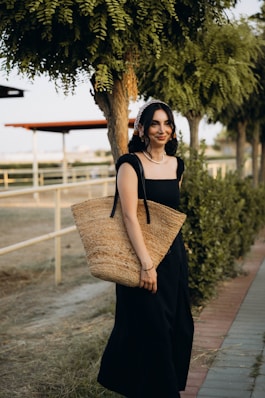 A woman in a black dress holding a straw bag