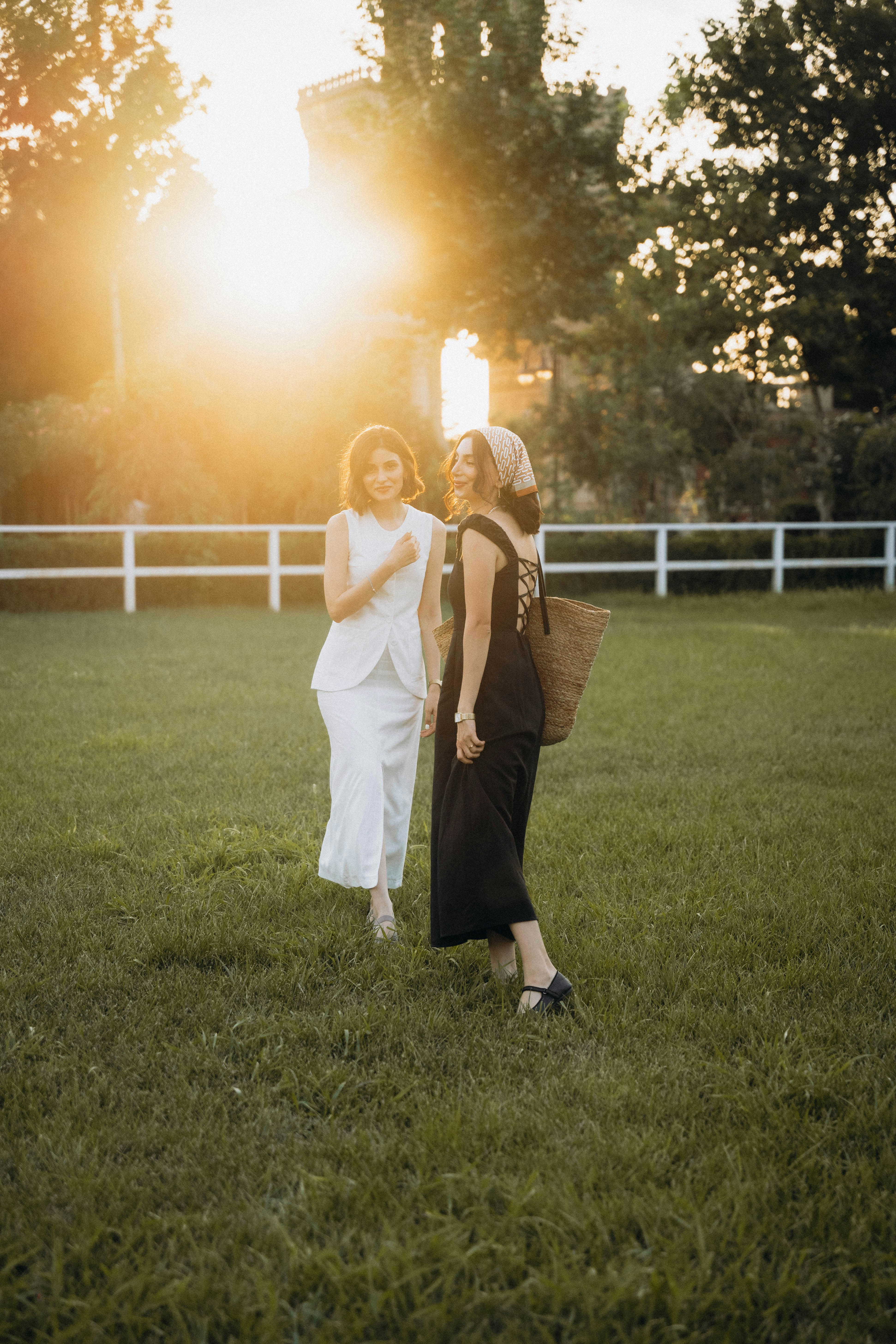 Two women standing in a field at sunset