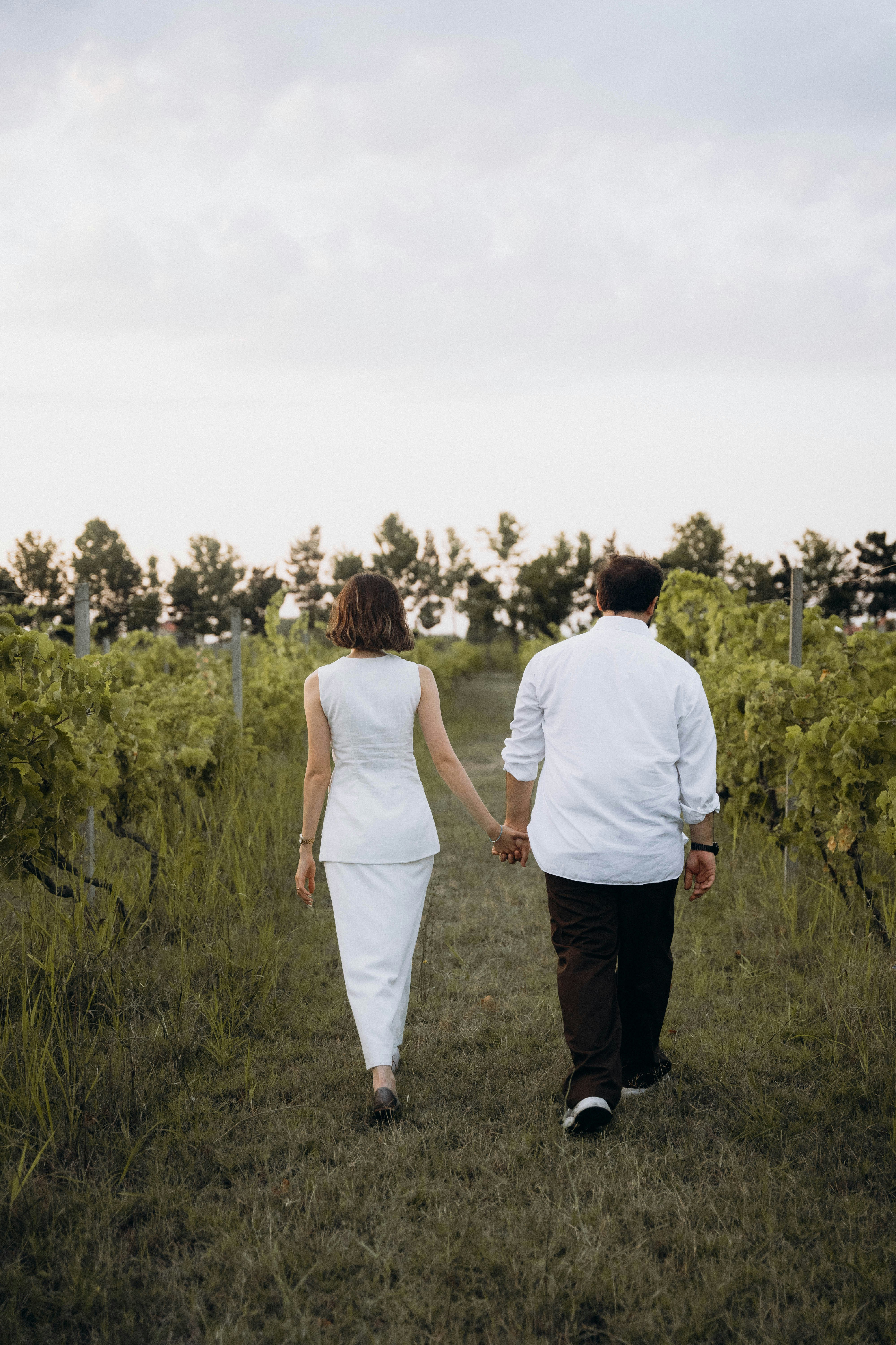 A man and woman walking through a field holding hands