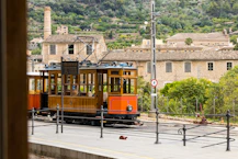 An orange trolley car traveling down a street
