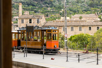 An orange trolley car traveling down a street