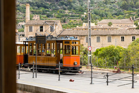An orange trolley car traveling down a street