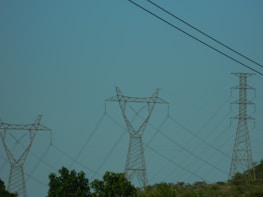 A plane flying in the sky over power lines