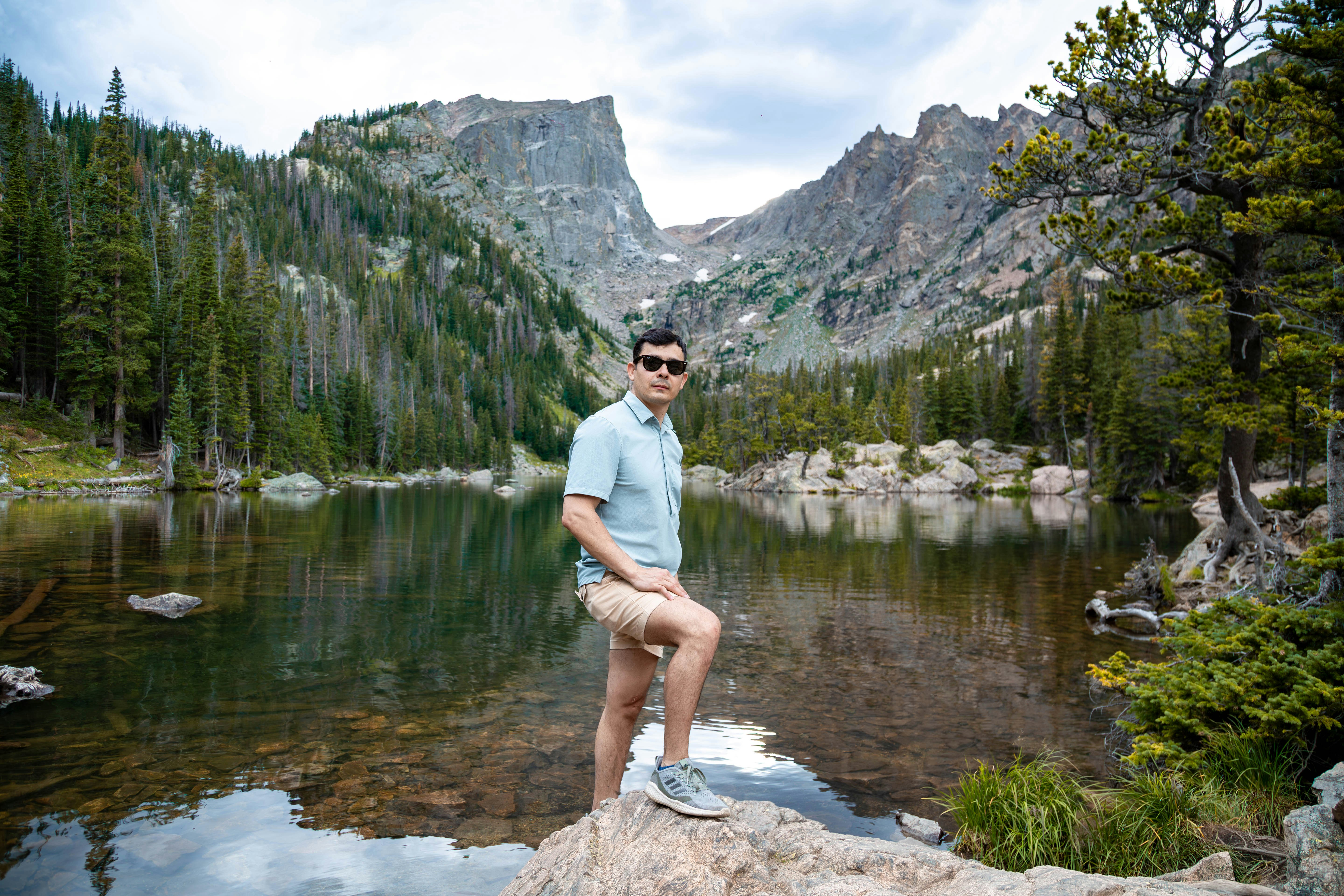 A man sitting on top of a rock next to a lake
