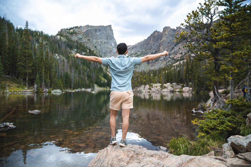 A UK sugar daddy standing on top of a rock next to a lake